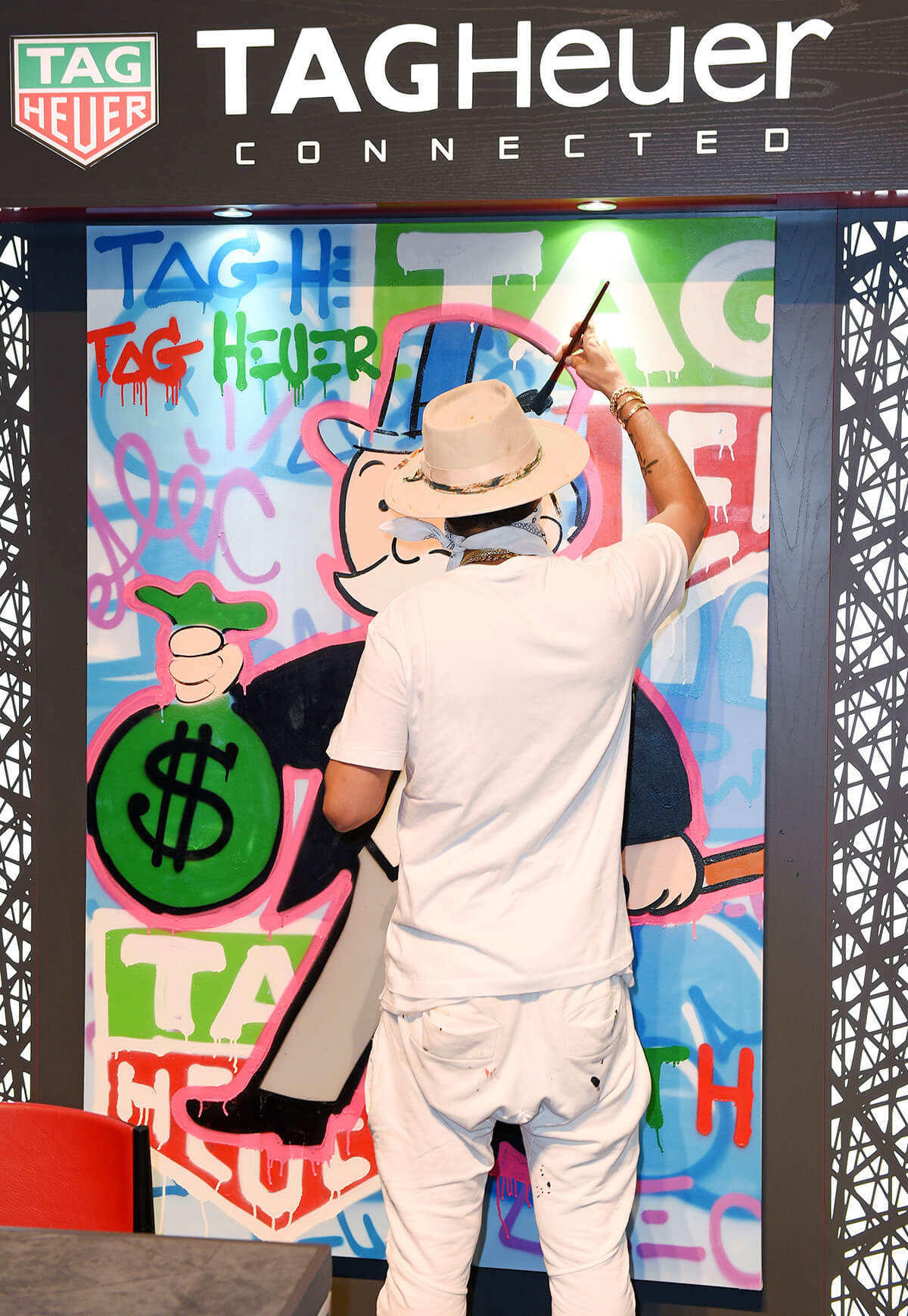 Street artist Alec Monopoly painting TAG Heuer onto wall