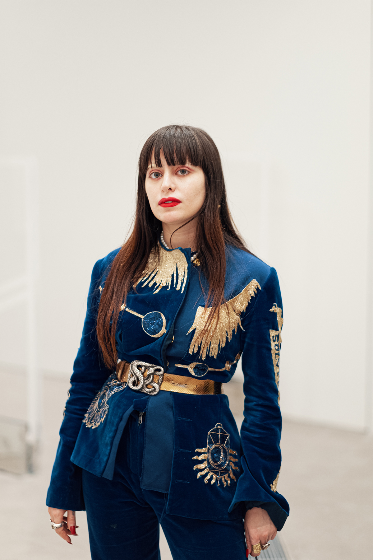 Woman standing in blue and gold blazer with red lips