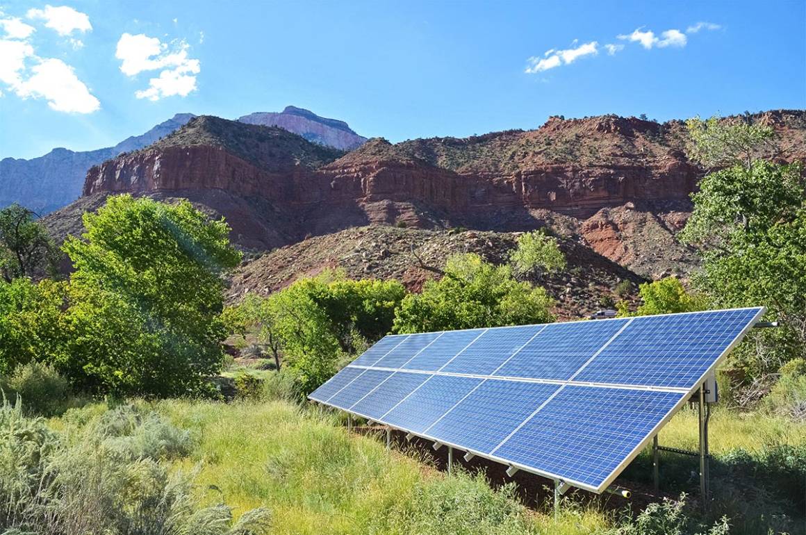 solar panel on the grass with rocky mountains behind it