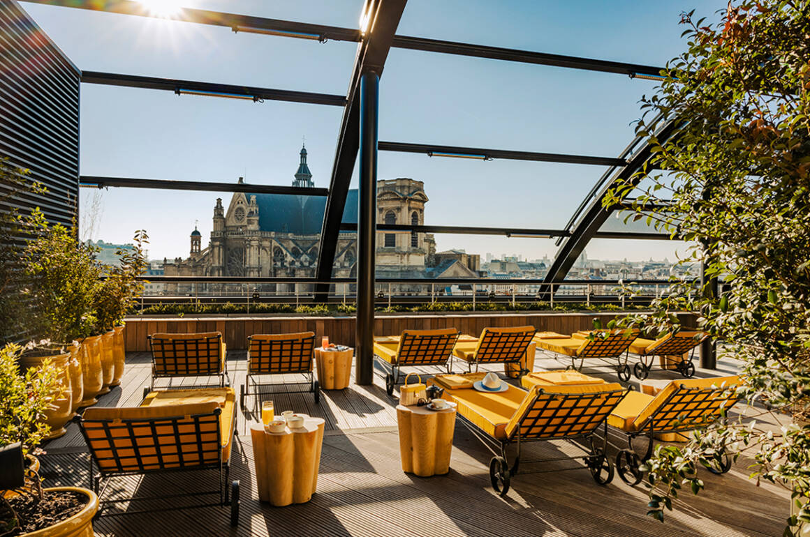 An outdoor terrace with yellow cushioned deck chairs and tables