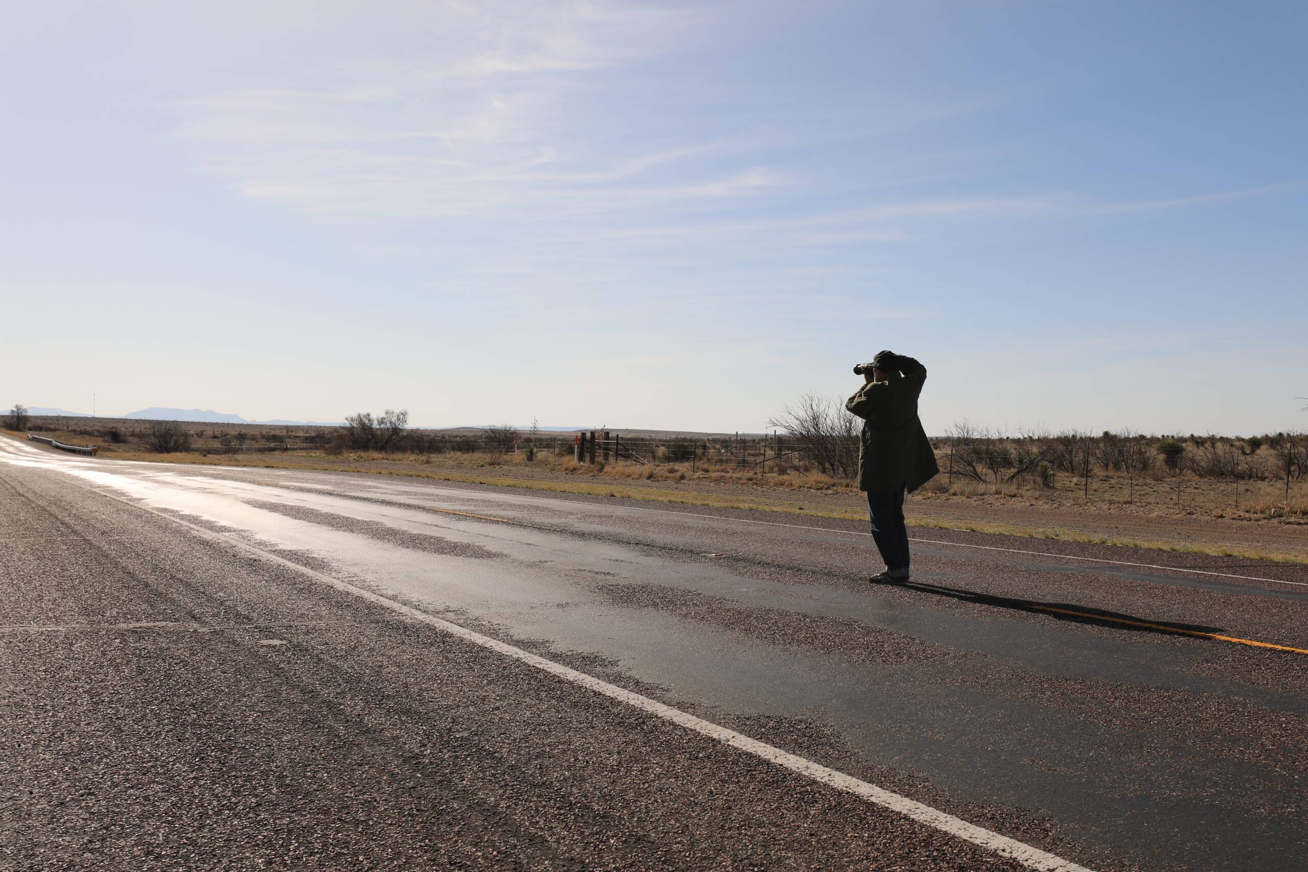 A man with a camera in hand taking a picture of the road ahead