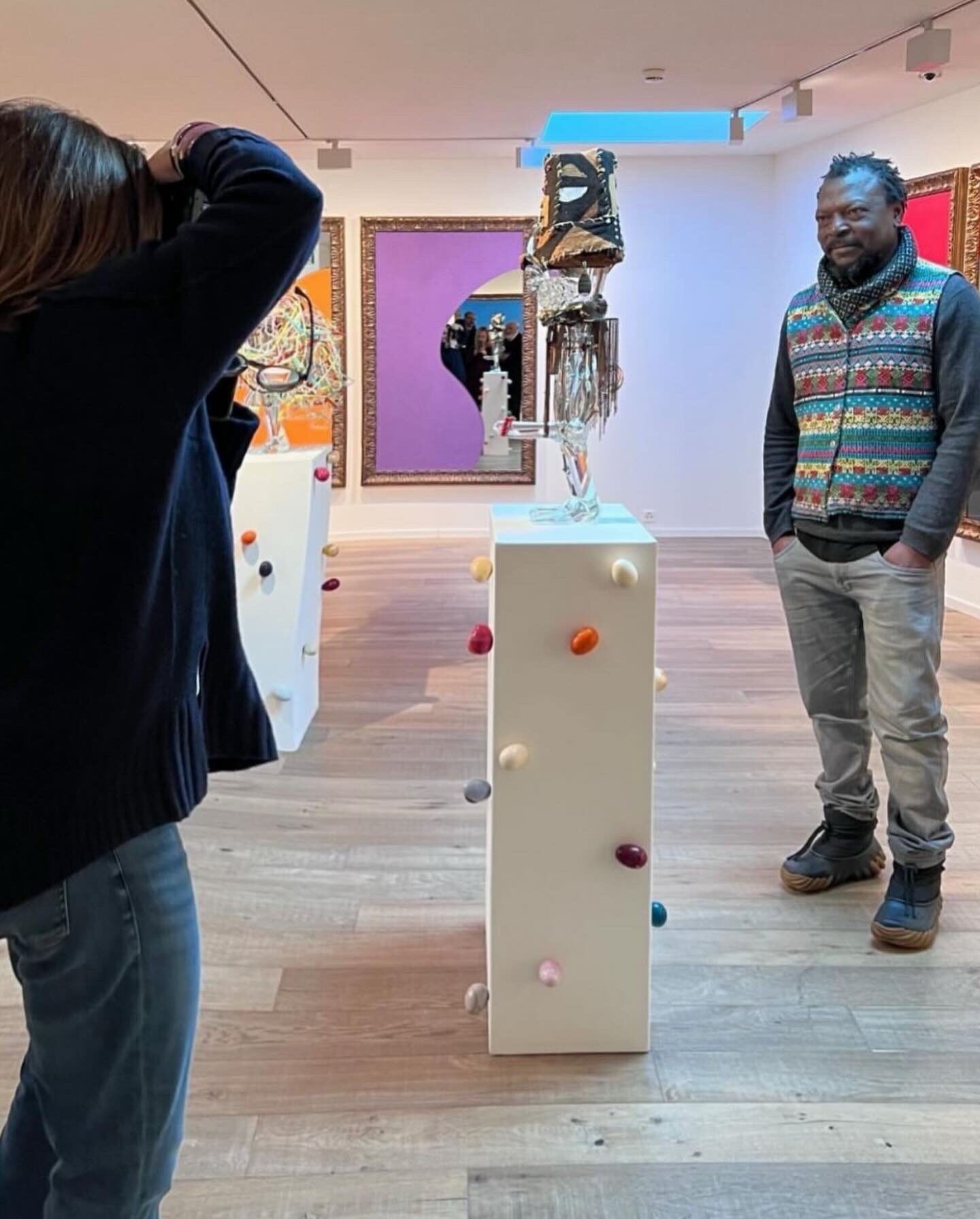 a woman takes a picture of a man in an art gallery