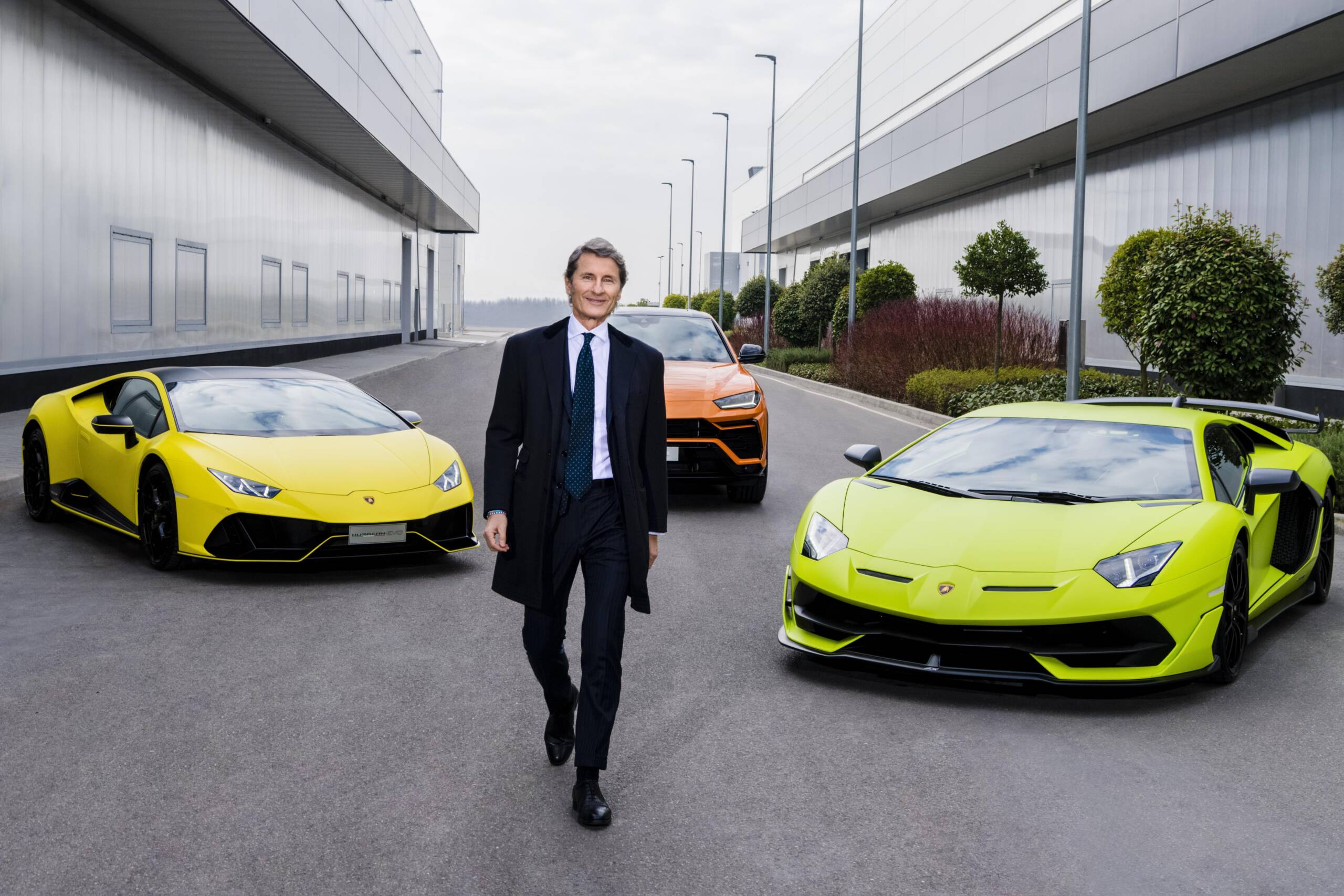 Man in a suit with cars behind him